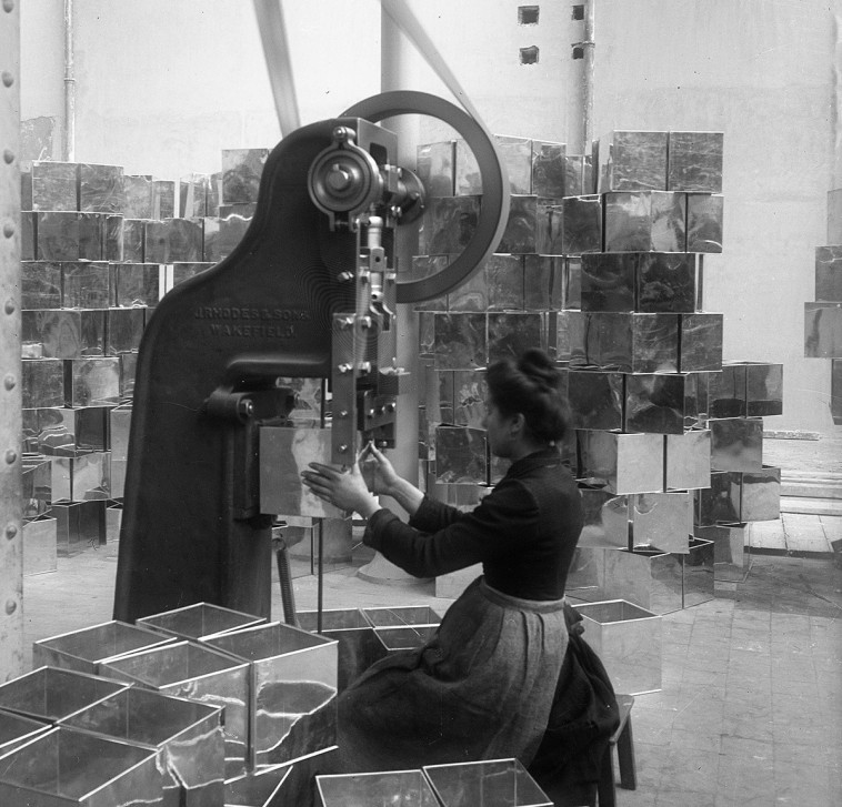 Photographie de femme devant une machine à l'usine